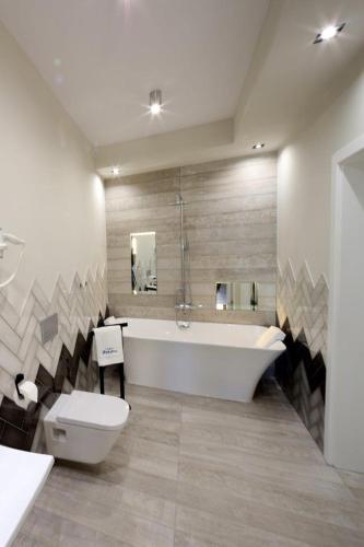 a bathroom with a tub and a toilet and a sink at Aparthotel Zakątna B&B in Tarnów