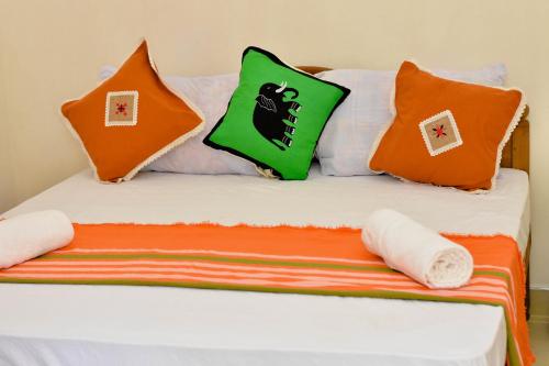 a bed with orange and green pillows on it at Kandy Dilruk Homestay in Kandy