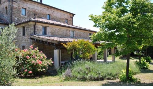 una antigua casa de piedra con un jardín delante de ella en Stone farmhouse in Moie, en Moie