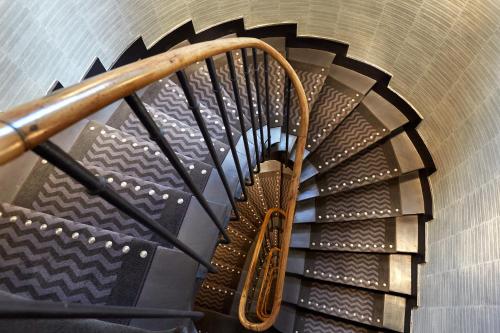 - un escalier en colimaçon dans un bâtiment avec un rail en bois dans l'établissement Hotel Antin Trinité, à Paris