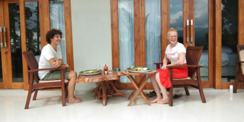 two women sitting around a wooden table in a room at Mandhasativa Homestay in Singaraja