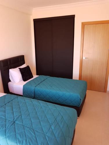 two beds sitting in a room with a door at Appartement Résidence Yassmina in Tangier