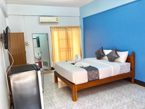 a bedroom with a bed with a blue wall at Anchisa Mansion in Phayao