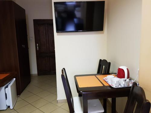 a dining room table with a television on a wall at Marcus in Bydgoszcz