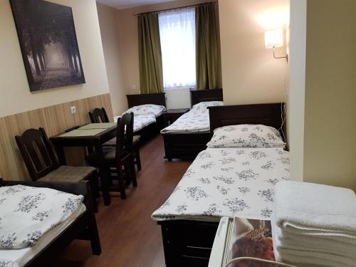 a room with three beds and a table and chairs at Marcus in Bydgoszcz