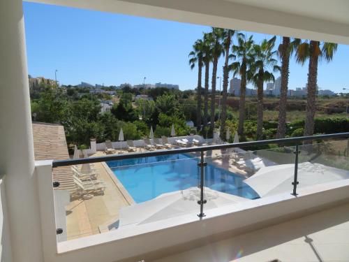 a view of a swimming pool from a balcony with palm trees at Hotel Alcaide in Portimão