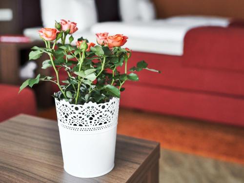 a white vase with red roses on a table at Hotel Lamm in Ostfildern