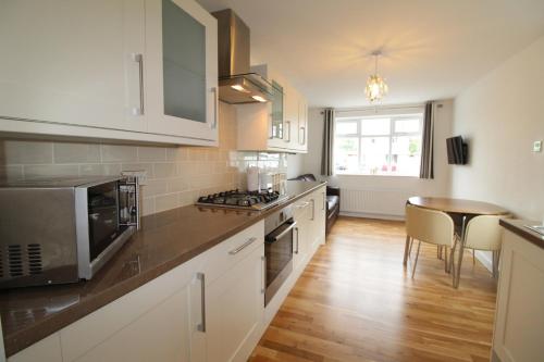 a kitchen with white cabinets and a table in it at The annex at 44 Belvidere Road in Shrewsbury