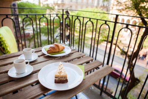 a table with a slice of cake and cups of coffee at Synagogue View Apartment in Budapest