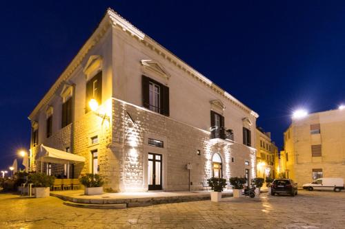 - un grand bâtiment blanc avec des lumières la nuit dans l'établissement Palazzo Filisio - Regia Restaurant, à Trani