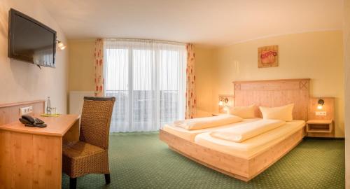 a bedroom with a bed and a desk and a television at Gasthaus Hotel Adler in Endingen