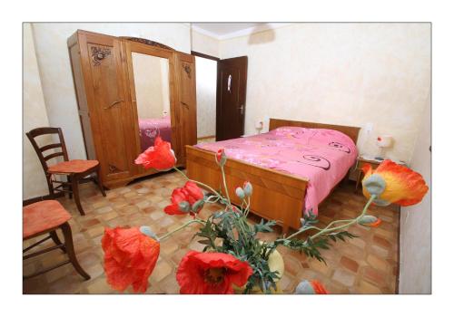 1 dormitorio con 1 cama con sábanas rosas y flores rojas en gîte la grange en Sainte-Croix