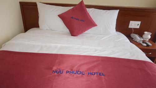 a bed with a red pillow on top of it at Khách sạn Hữu Phước in Quy Nhon