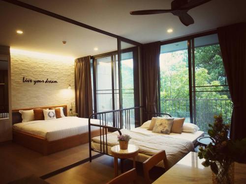 sypialnia z 2 łóżkami i dużym oknem w obiekcie Live Your Dream Khaoyai w mieście Phayayen