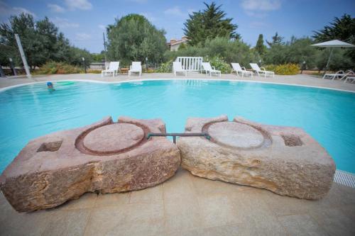 a swimming pool with a rock in the middle at Casale La Macina - Hotel, Scopello in Scopello