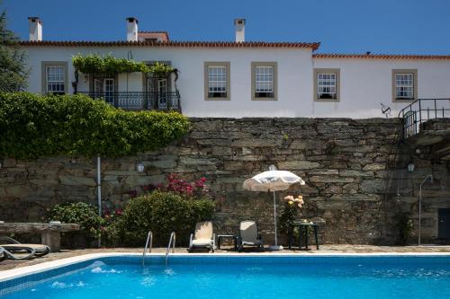 a pool with two chairs and an umbrella and a house at Casa De Casal De Loivos in Pinhão