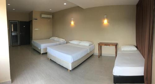 a room with two beds and a table in it at Pantai GuestHouse in Kuantan