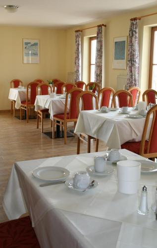 a dining room with white tables and red chairs at Apparthotel Garni Superior Simsseeblick in Bad Endorf