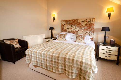 a bedroom with a bed with a plaid blanket and a chair at Eltermere Inn in Elterwater