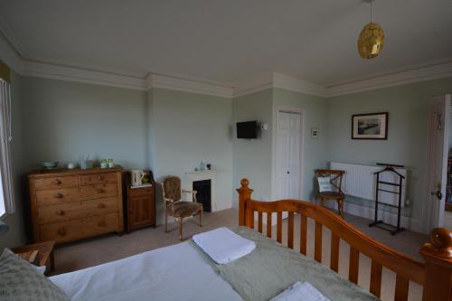 a bedroom with a bed and a dresser and a fireplace at Severn House in Watchet