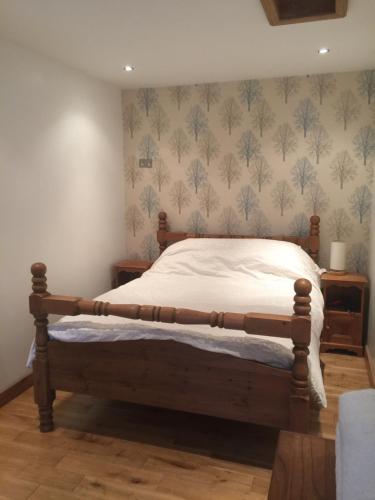 1 dormitorio con 1 cama con marco de madera en The Old Vicarage Lodge en Mánchester