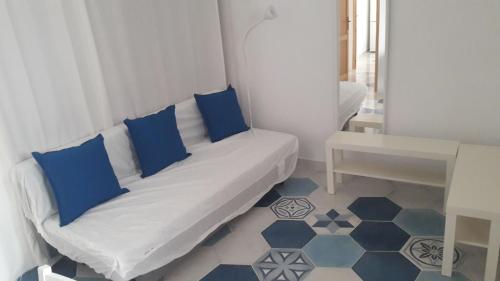 Sofá blanco con almohadas azules en una habitación en La casa dei cugini, en Santa Marina Salina