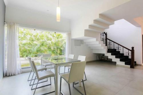 a dining room with a table and chairs and a staircase at Mansions by Pinto Rosario in Bastora
