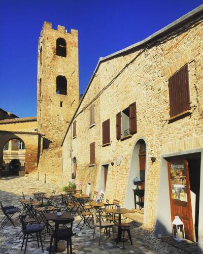 a building with tables and chairs next to a tower at Malatesta Antica Dimora in Longiano