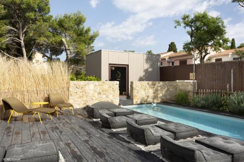 a backyard with a pool and chairs and a house at Le 19-21 - Un amour d'hotel in Leucate