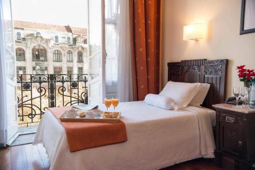 a hotel room with a bed with a tray of food on it at Hotel Aliados in Porto