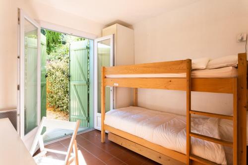 サン・シル・シュル・メールにあるT3 Rez de Jardin,Piscine Privéeのベッドルーム1室(二段ベッド2組付)、バルコニーが備わります。