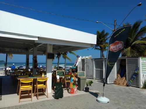a restaurant on the beach with yellow chairs at Pippo Suites Guarujá in Guarujá