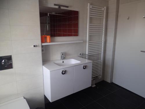 a white bathroom with a sink and a mirror at Les Gîtes de la tour, appartement "le Vignoble" in Saint-Hippolyte