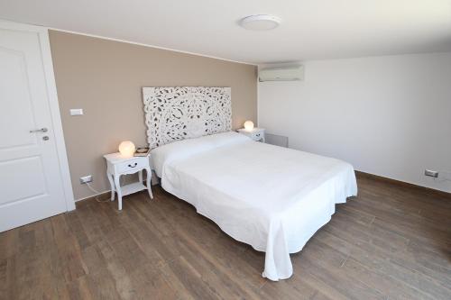 a white bedroom with a white bed and two tables at villa aurora in Giardini Naxos