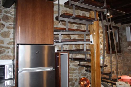 a kitchen with a stainless steel refrigerator next to a stone wall at El Nidito de Fermoselle in Fermoselle