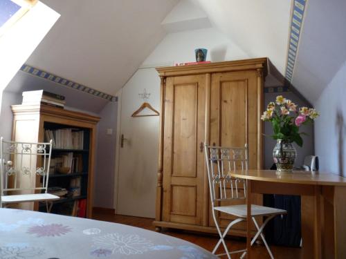 Habitación con mesa, sillas y armario de madera. en Le Petit Grenier, en Bayeux