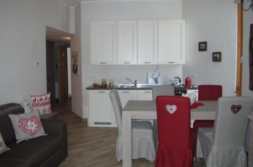 ブレウイル・チェルヴィナイアにあるFrazione Breuil Cerviniaのキッチン(白いキャビネット、テーブル、赤い椅子付)