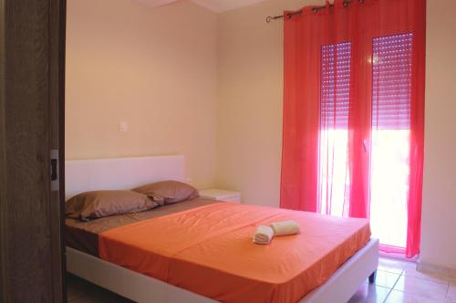 a bedroom with a bed with orange sheets and red curtains at Spiridoula's Apartments Corfu in Perama