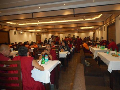 a group of people sitting at tables in a restaurant at Niranjana Hotel Bodhgaya in Bodh Gaya