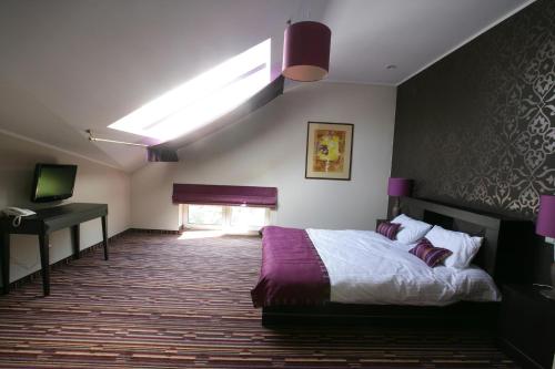 a bedroom with a bed and a desk and a window at Hotel Atena Wedding, Business & Spa in Ciechanów
