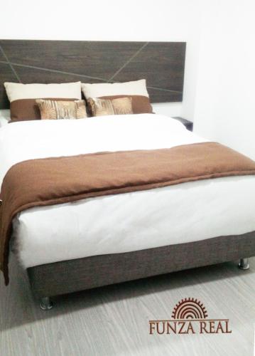 a large bed with white sheets and brown pillows at Hotel Funza Real in Funza