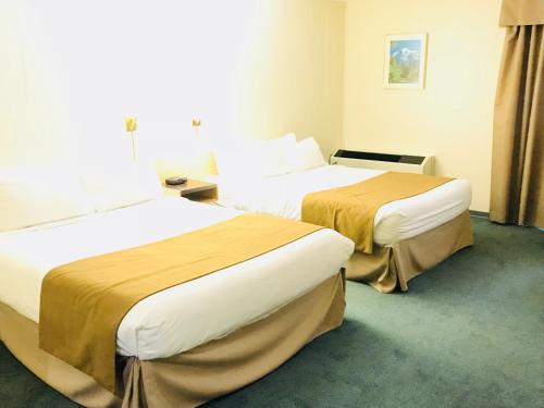a hotel room with two beds in a room at Northern Star Hotel & Convention Center in Slave Lake