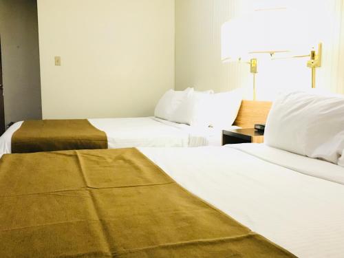 two beds in a hotel room with white sheets at Northern Star Hotel & Convention Center in Slave Lake