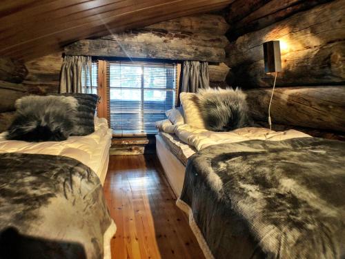a bedroom with two beds in a log cabin at Ruka Chalet Petit Oliver in Ruka