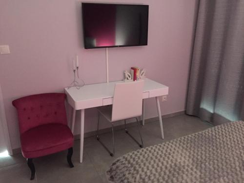 a bedroom with a desk and a chair and a tv at La chambre rose in Mâcon