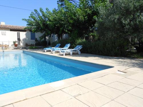 una piscina con 2 tumbonas junto a ella en Le Mas des Lavandes, en Le Pègue