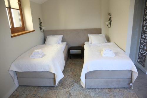 two beds with white sheets in a room at Aparthotel Zakątna B&B in Tarnów