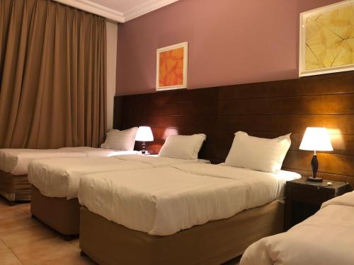 a hotel room with two beds and two lamps at Manazel Alaswaf Hotel in Al Madinah