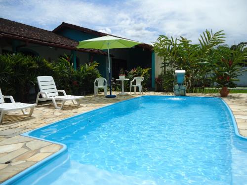 een zwembad met stoelen en een parasol naast een huis bij Mata Atlântica Chalés - Praia da Lagoinha, Ubatuba - SP in Ubatuba