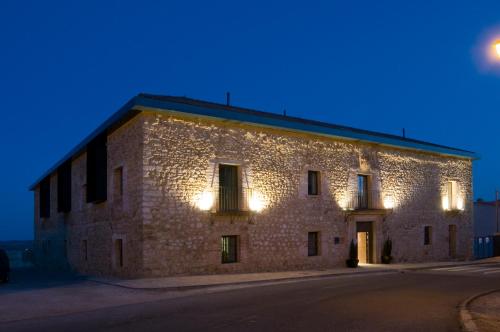 an old stone building with lights on it at night at Hospedium Hotel Convento de Santa Ana in Atienza